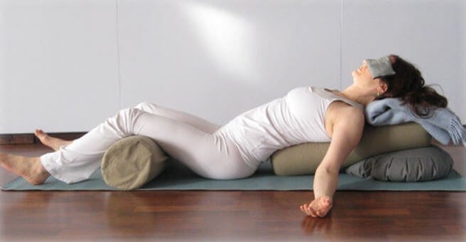 woman relaxing in a restorative yoga pose